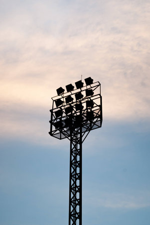 The silhouette of stadium light stand set against a blue sky with white clouds.の写真素材