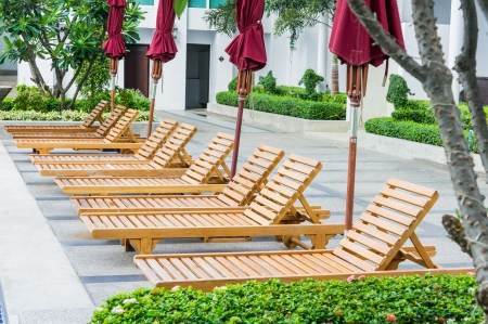 chair and swimming pool surrounded by tropical plantsの写真素材