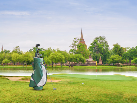 Golf bag ,golf ball and golf clubs,putter, equipment on green at golf course on pagoda as backgroundの写真素材