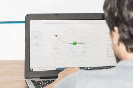 a guy checking a graphic about the coronavirus on his computerのeditorial素材