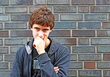Portrait of the young man against a brick wallの写真素材