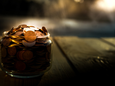 Coins in glass on the wooden background, financial concept