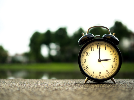 Close up an alarm clock with nature background, time concept