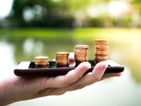 Close up stack of money coins on the mobile phone, business in eCommerce conceptの写真素材