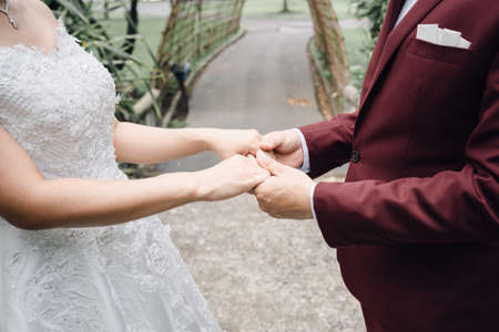 Bride and groom happy newly wedding couple hold hands together in the garden without face, happy wedding concept.の写真素材