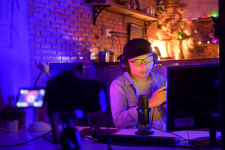 Asian female video blogger,woman vlogger makes a video stream on the couch at home.professional video shooting for streaming services,の写真素材