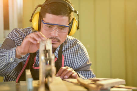 Selective focus of handsome man in goggles and apron in workshop,Carpenter workingの写真素材