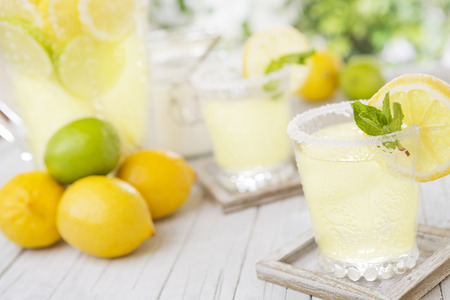 Refreshing homemade lemonade on a rustic outdoor table in bright light.の写真素材