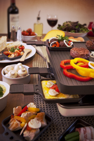 Swiss raclette or the Dutch variant 'gourmetten'. A table filled with ingredients for a dish that is usually served on celebratory evenings like Christmas or New Years Eve in The Netherlands.の写真素材