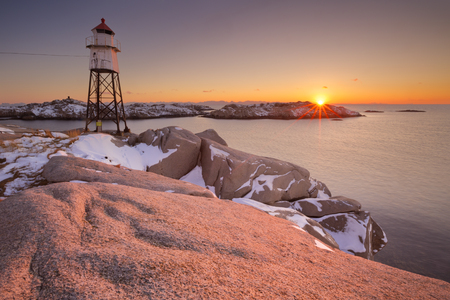 A lighthouse on the cliffs on the Lofoten in northern Norway at sunrise.の写真素材