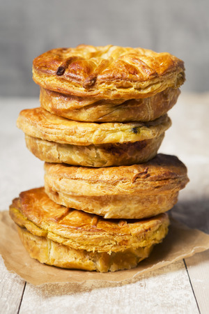 A stack of homemade meat pies on a rustic table.の写真素材
