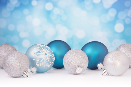 Blue and silver Christmas baubles in front of defocused purple and white lights.の写真素材