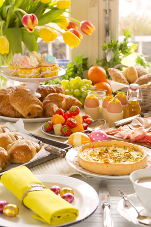 Breakfast or brunch table filled with all sorts of delicious delicatessen ready for an Easter meal.の写真素材