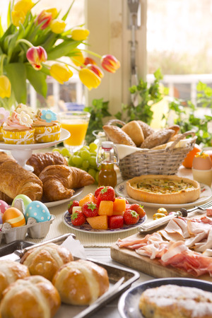 Breakfast or brunch table filled with all sorts of delicious delicatessen ready for an Easter meal.の写真素材
