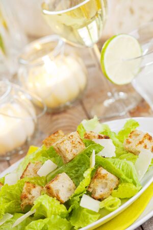 A plate with a fresh Caesar salad on a rustic table in bright light.の写真素材