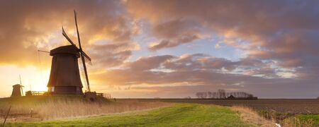 Traditional Dutch windmills at sunrise near Schermerhorn in The Netherlands.の写真素材