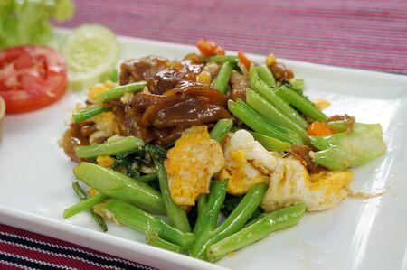 Noodles fried with pork in soy sauce on white plate.の写真素材