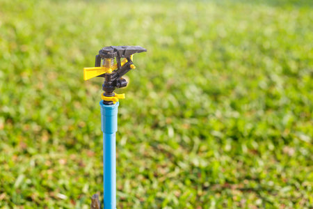 sprinkler in green grass gardenの写真素材