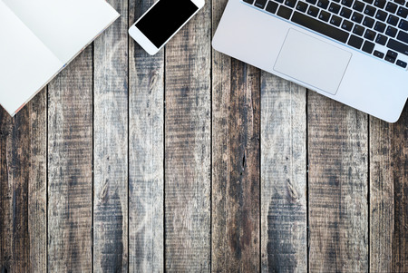 Laptop,notebook and mobile phone top view on old wood plank background have space.