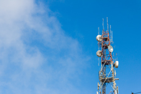 telecommunication tower antenna with blue sky and cloud background.