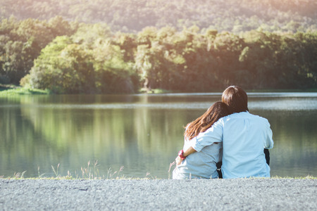 Valentine couple sit at riverside in garden while sunset.の写真素材