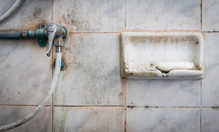 Soap and valve of shower in dirty bathroom.の写真素材