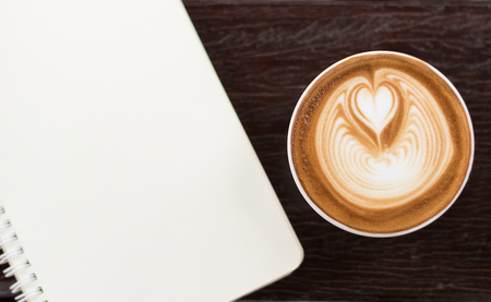 Top view coffee latte art with bank notebook on wood table vintage tone.の写真素材