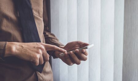 Businessman standing near window and using cell phone vintage tone.の写真素材
