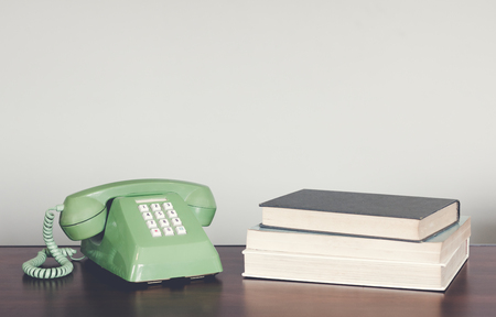 Retro green telephone on wood table with book vintage tone.の写真素材