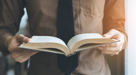 Businessman standing near window and reading book vintage tone.の写真素材