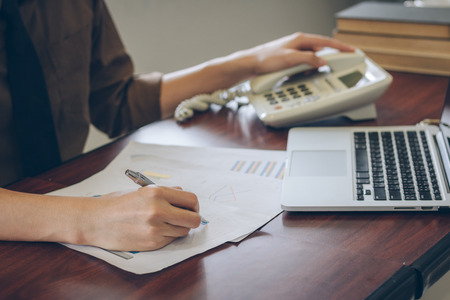 Close up businessman analyzing graph document with laptop and telephone.の写真素材
