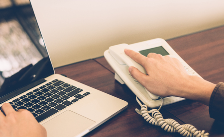 Businessman using telephone contact customer in office vintage tone.の写真素材