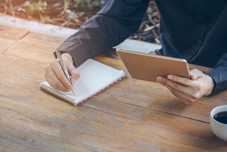 Close up businessman using tablet working in coffee shop.