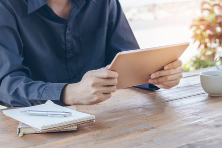 Close up businessman using tablet working in coffee shop.の写真素材
