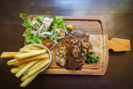 Top view grilled Pork Steak with french fries, salad on wooden plate.の写真素材