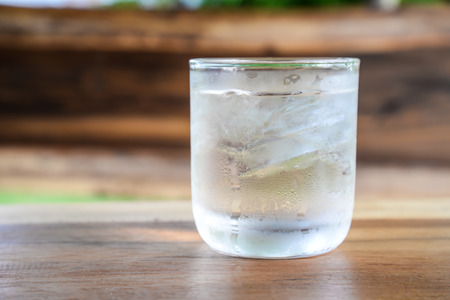Place the glass with ice on a wooden table.の写真素材