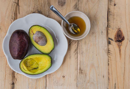 Avocado halves on a plate with white. And honey, put on the wood floor left.の写真素材