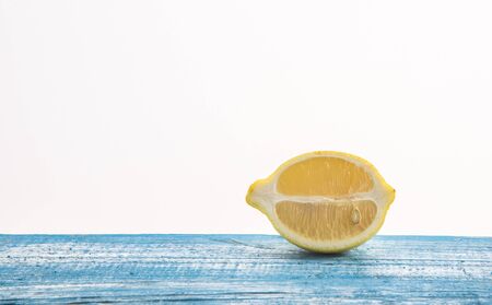 yellow lemon cut in half, put on a blue wooden floor on the right. Fuzzy white background.の写真素材