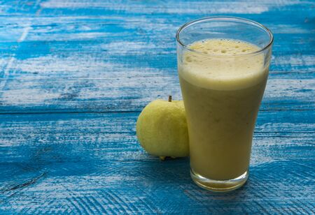 Guava Smoothie placed on a wooden floor in blue on the right. Focus on glass.の写真素材