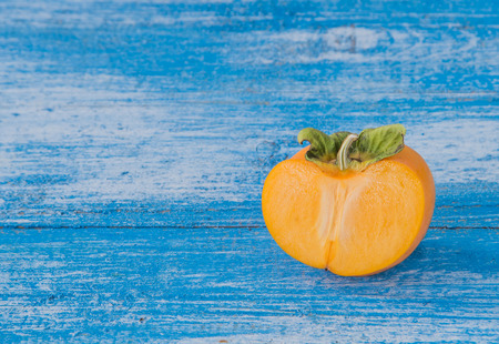 Fresh Persimmon cut in half Place the timber on the ground, blue and white. Focus Persimmon.の写真素材