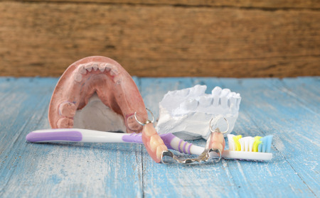 Denture mold,false teeth,old toothbrushes placed on wooden floor.
