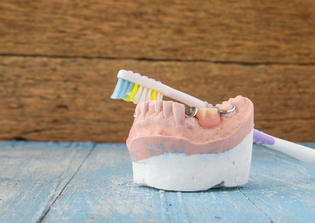 Denture mold,false teeth,old toothbrushes placed on wooden floor.