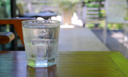 Glass water placed on wooden floor,blur background.focus top glass water.Shiny green glass shade.の写真素材