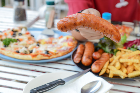 pizza,Send a sausage by hand ,French fries,Vegetables on iron table.の写真素材