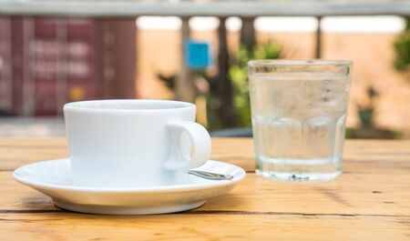 White coffee cup,Glass water placed on wooden floor.Focus coffee cup.の写真素材
