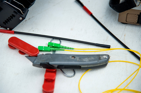 Fiber optic Pigtail with Cutter and shrink tube on white floor.