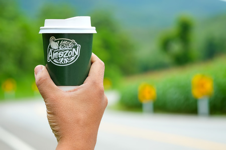 CHIANGMAI, Thailand - September 7, 2016 : Amazon take away coffee cup in manhand with blurred road background.のeditorial素材