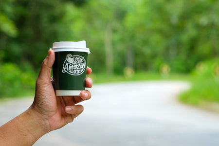 CHIANGMAI, Thailand - September 7, 2016 : Amazon take away coffee cup in manhand with blurred road background.のeditorial素材