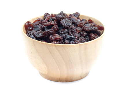 Dried grapes in wood bowl on white background.の写真素材