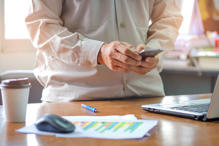 Man office staff using smart phone with analyzing graphs.